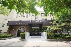A hotel entrance with a modern facade, a staircase leading up to the entrance, and a sign in both Chinese and English. - Ji Hotel (Shanghai)