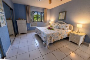 A bedroom with a bed, bedside tables, a window, and a dresser. - Comfy condo minutes from downtown & Free Parking (Christiansted)