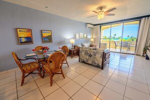 A hotel room with a dining area, a sofa, a ceiling fan, and a large sliding glass door leading to a balcony with a view. - Comfy condo minutes from downtown & Free Parking (Christiansted)