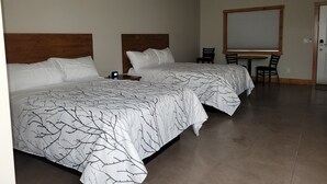 Habitación de hotel con dos camas, un escritorio y una silla.