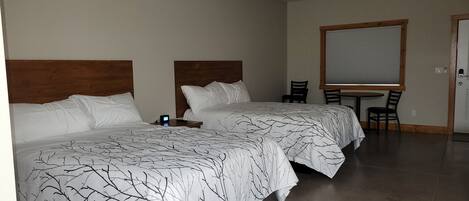 A hotel room with two beds, a desk, and a chair.