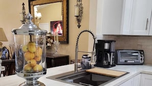 Una cocina moderna con armarios blancos, lavavajillas, cafetera y tostadora.