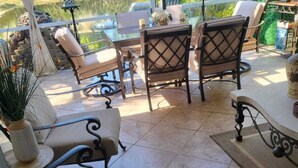 Un patio con mobiliario exterior, incluyendo un sofá y sillas, una mesa y una planta decorativa.