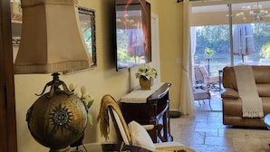Una sala de estar con una mesa de centro de vidrio, una lámpara, un sofá y un televisor.