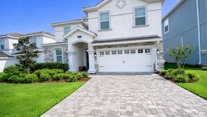 A two-story house with a garage, a stone facade, and a well-maintained lawn.