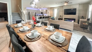 A modern dining area with a wooden table set for four, surrounded by chairs.