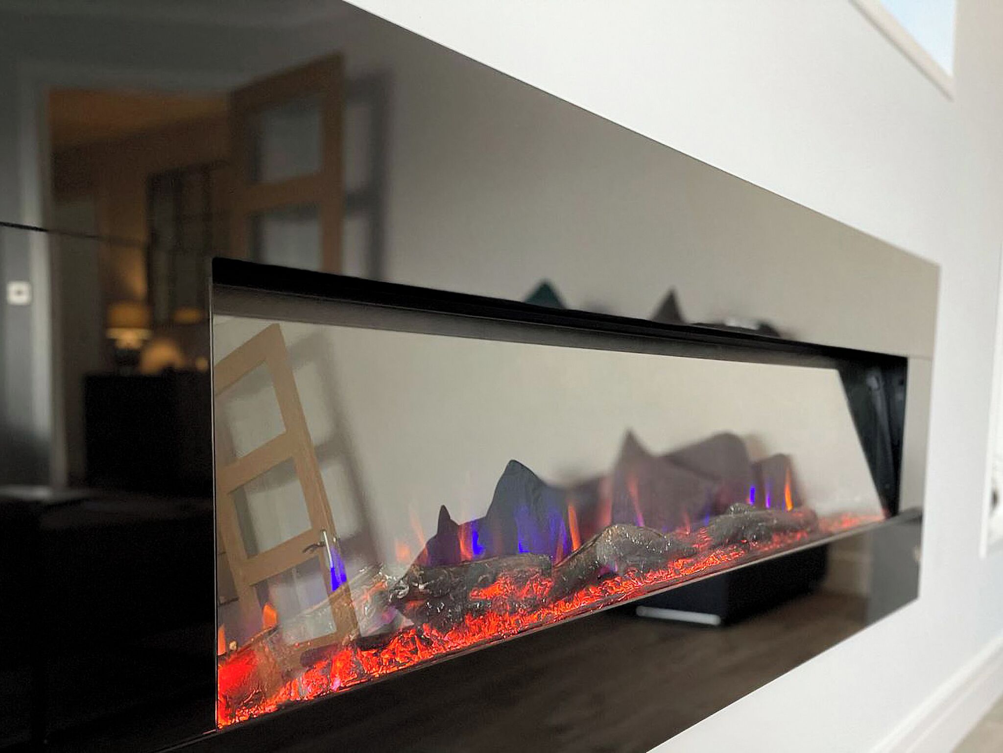 Ein moderner Kamin mit Glasfront, eine Holzleiter und eine dekorative Steinanordnung.