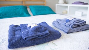 Un lit bien fait, avec des serviettes bleues et une couette blanche.