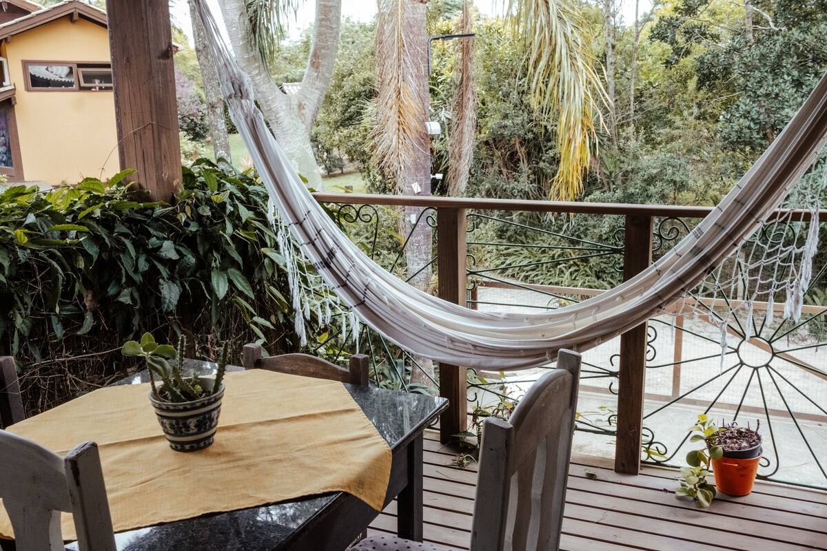 Eine Holzterrasse mit einer Hängematte, einem Tisch mit Tischdecke und Blumentöpfen.