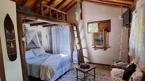 Ein rustikaler Raum mit einem Bett, einem Holzstuhl, einem kleinen Tisch und einem Fernseher.