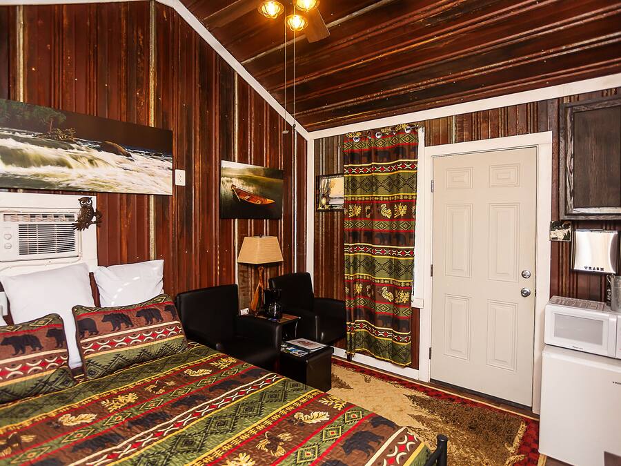 A room with a bed, a desk, a chair, a television, a door, and a microwave.