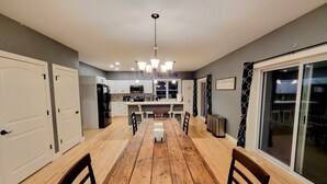 Una cocina moderna con armarios blancos, una mesa de comedor de madera y una lámpara de araña.