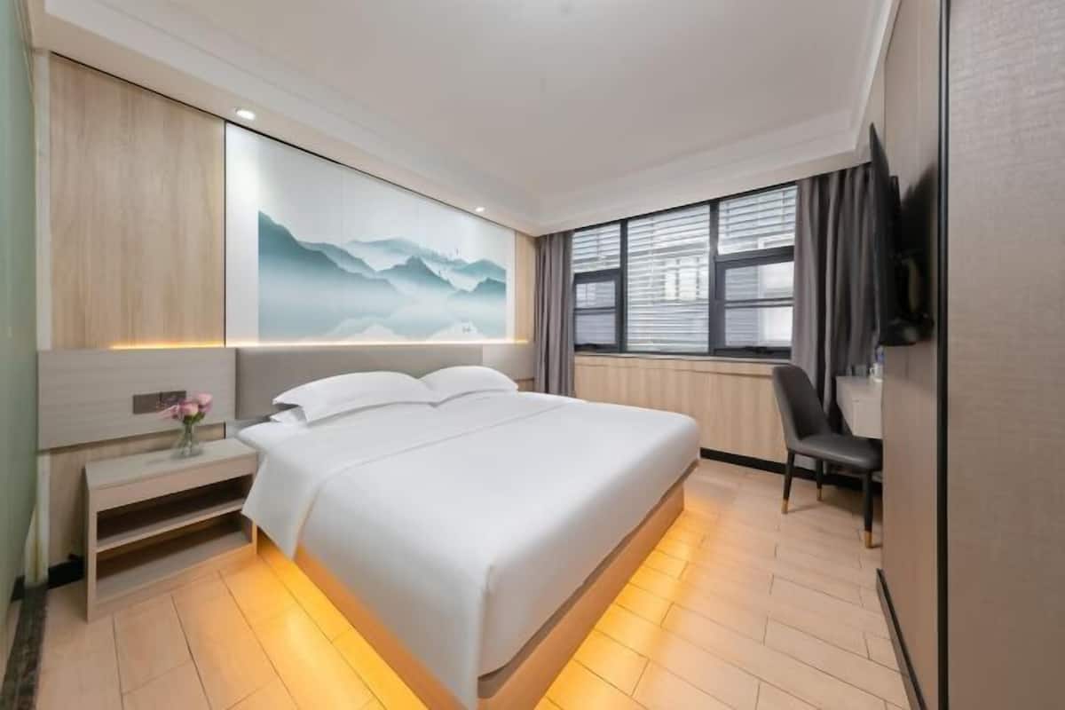 A hotel room with a large bed, bedside tables, a desk, and a TV.