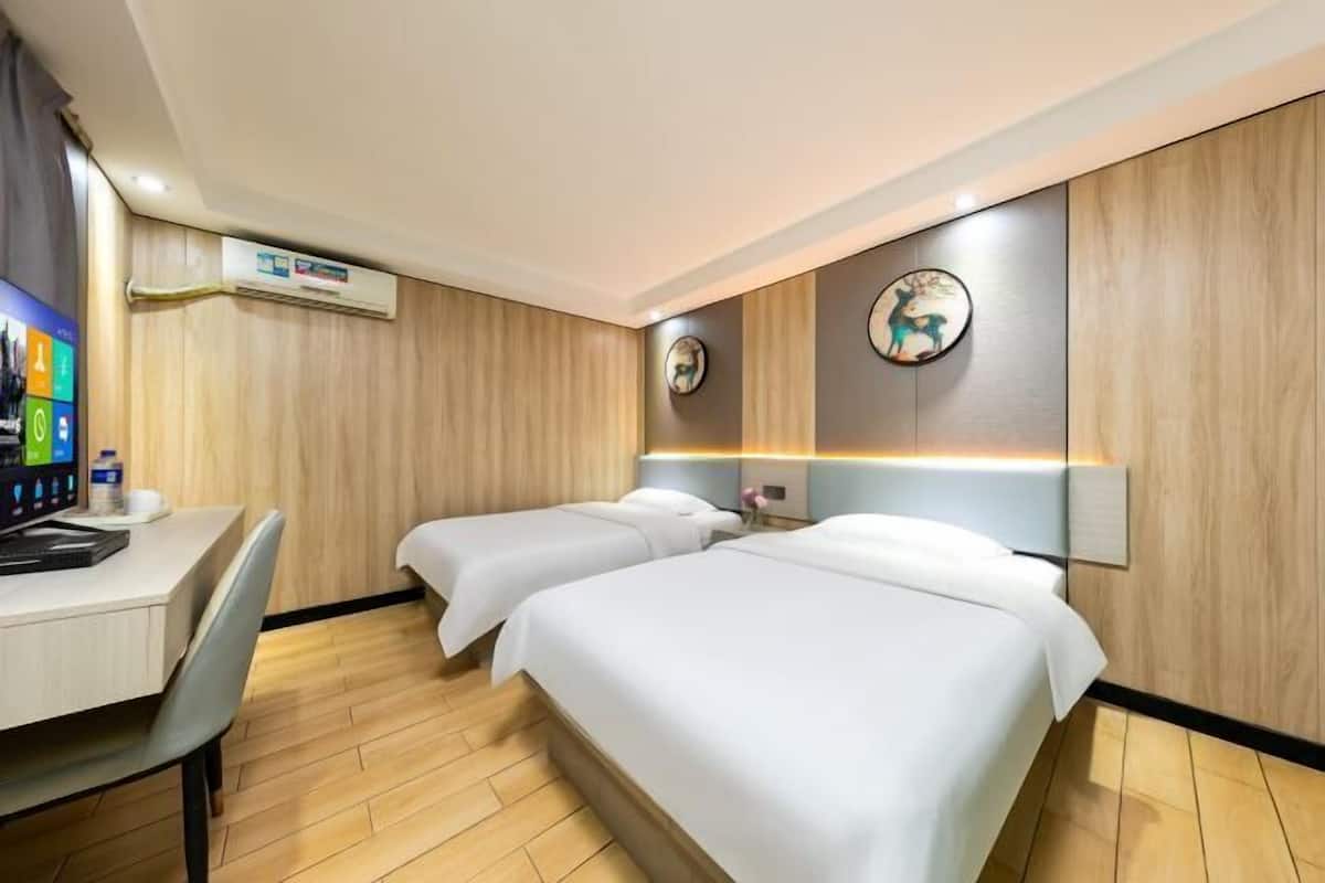 A hotel room with two beds, a desk, and a computer.