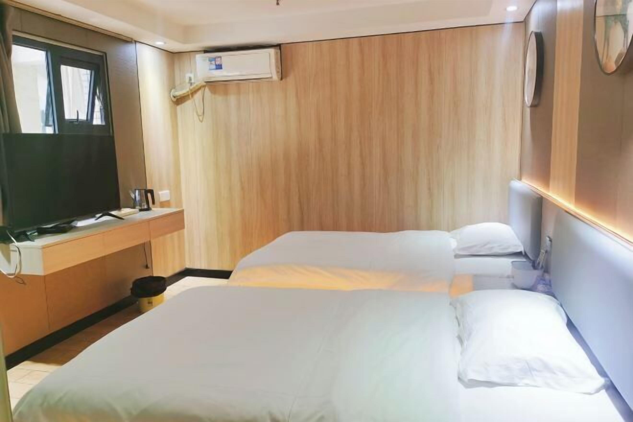 Una habitación de hotel con una cama grande, un escritorio con televisor y un panel de pared de madera.