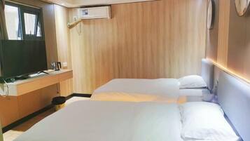 Una habitación de hotel con una cama grande, un escritorio con televisor y un panel de pared de madera.