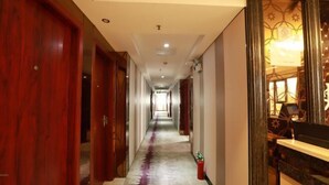 A hotel hallway with wooden doors, a fire extinguisher, and a reception desk. - Alice Hotel (Guangzhou Olympic Sports Chebei Subway Station Branch) (Guangzhou)