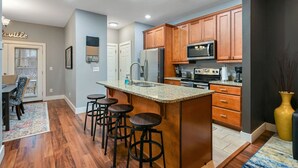 A modern kitchen with wooden cabinets, a granite countertop, and a built-in microwave.