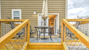 A wooden deck with a metal railing, a table, and chairs.