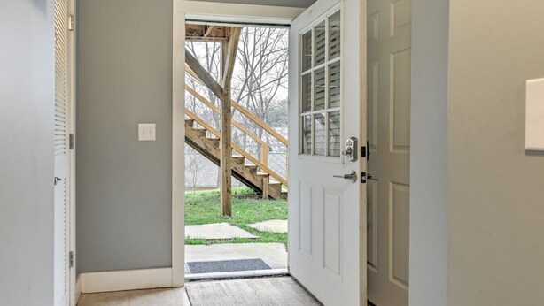 A hallway leading to a wooden staircase and a white door.