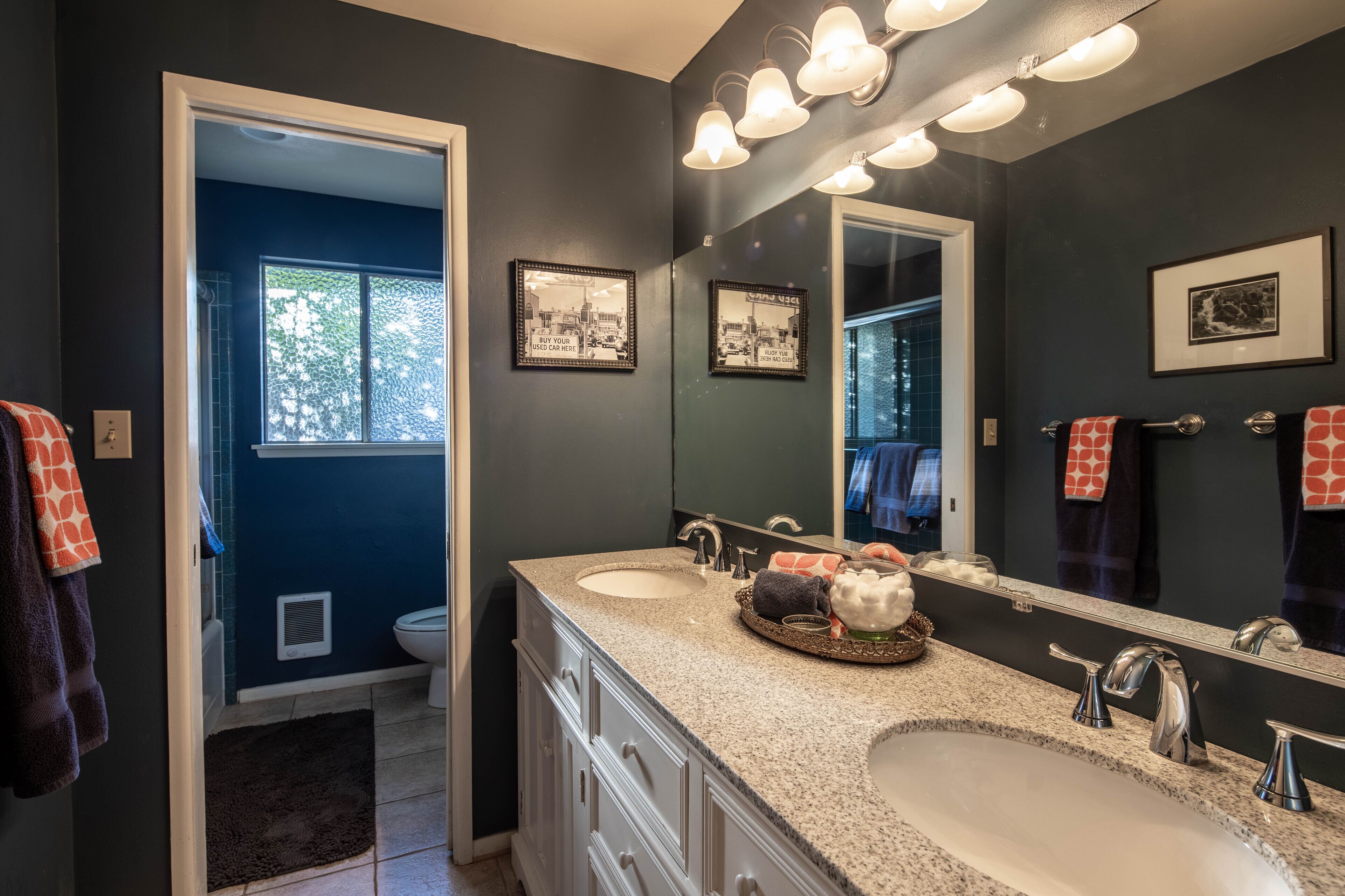 A bathroom with a double sink, a large mirror, and a vanity with a tray of toiletries.