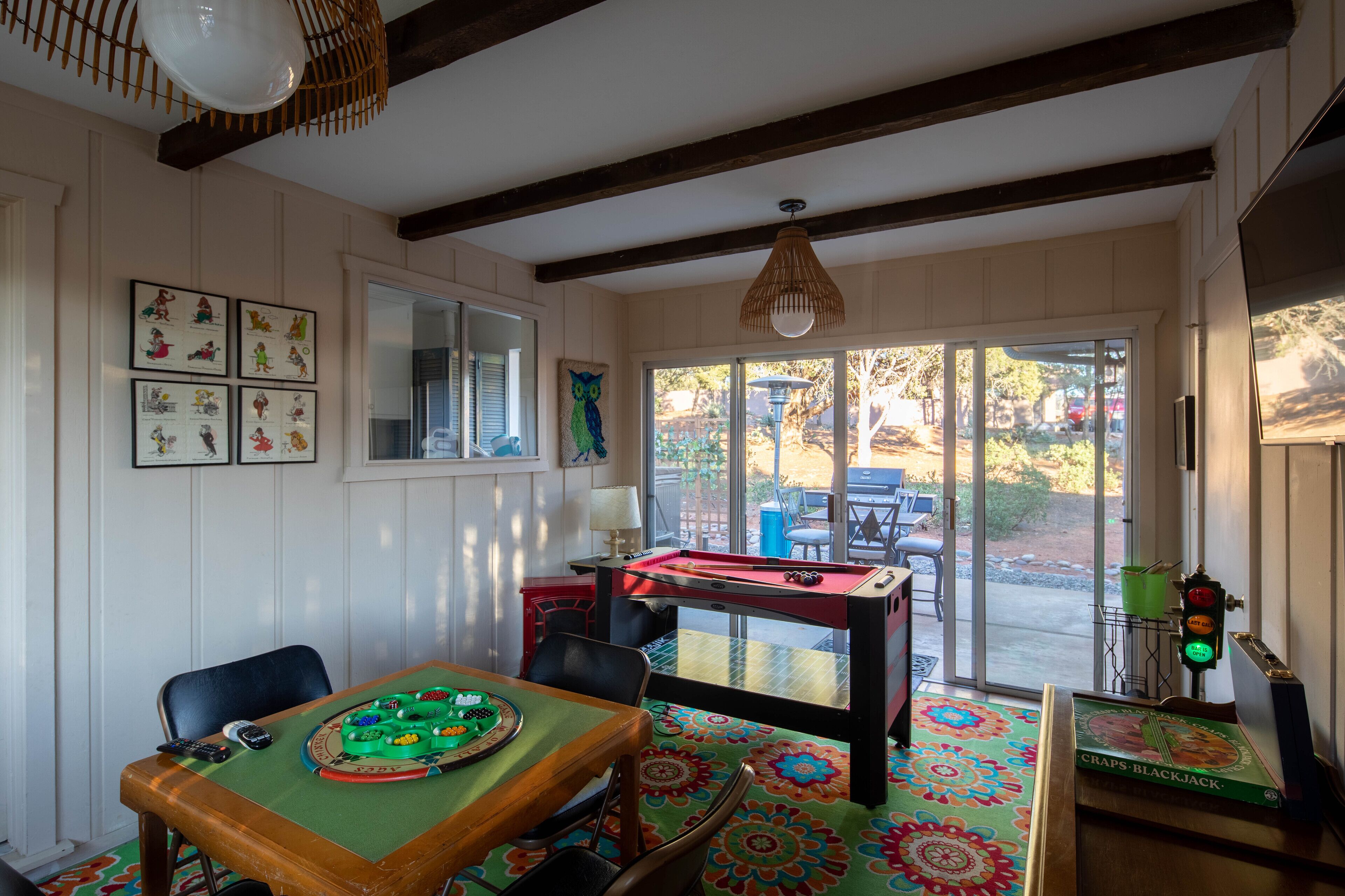 A room with a pool table, a green felt table, and a colorful patterned rug.