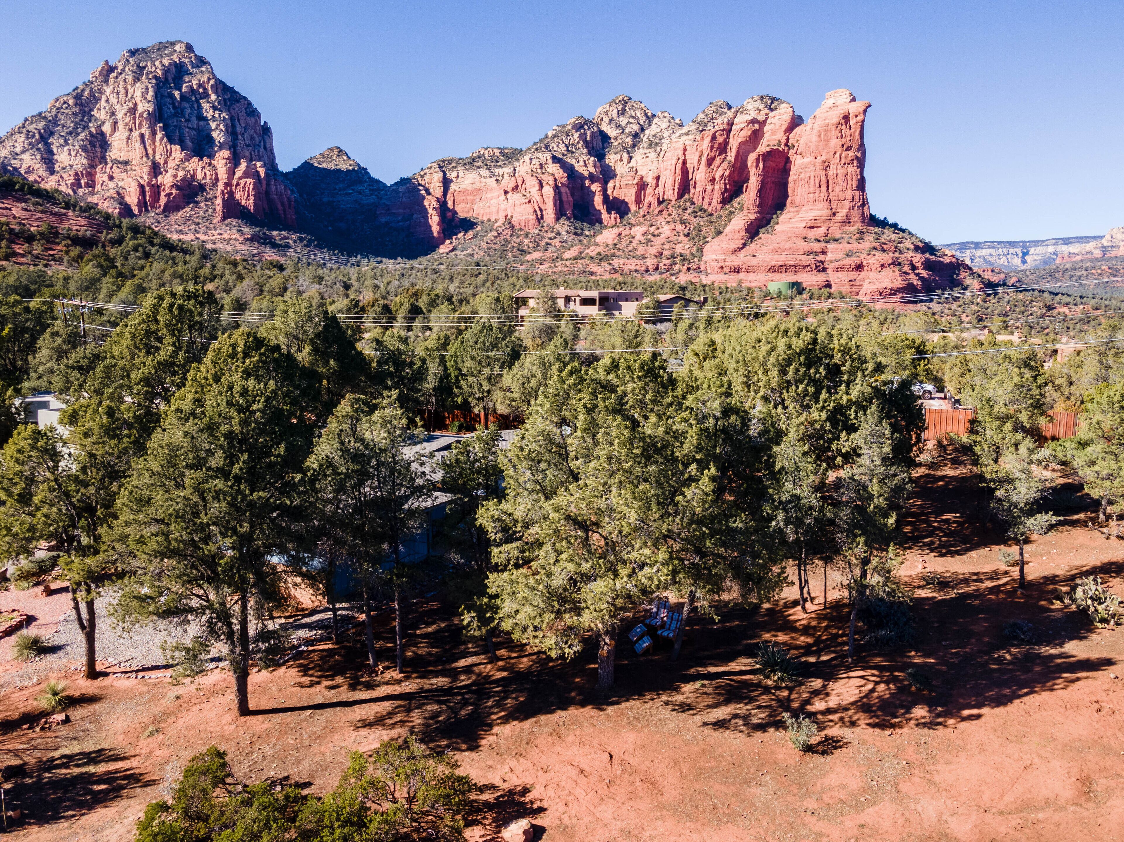 A mountainous landscape with red rock formations, a small settlement with houses, and dense green trees.