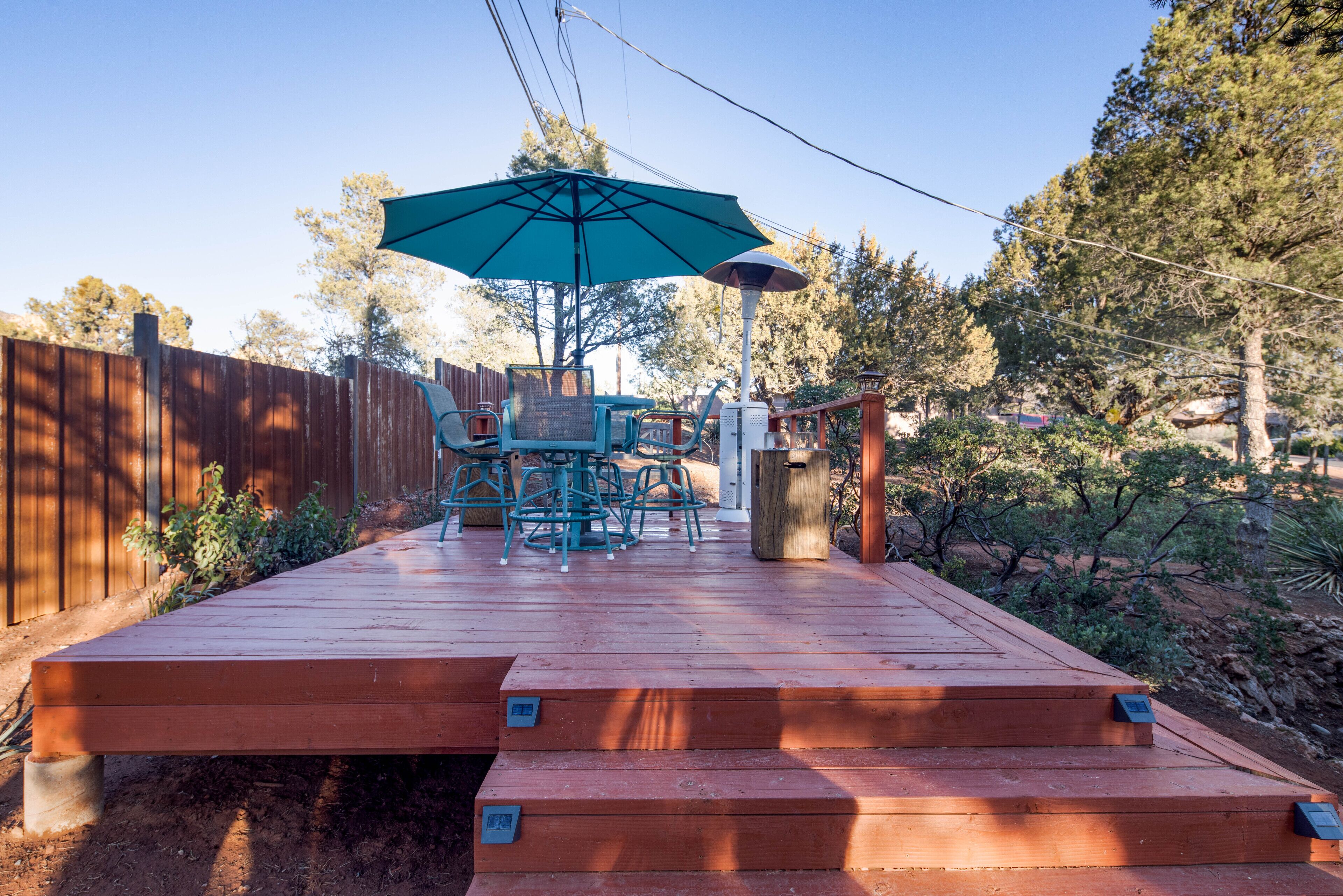 A wooden deck with outdoor furniture, including chairs and a table, and a large umbrella.