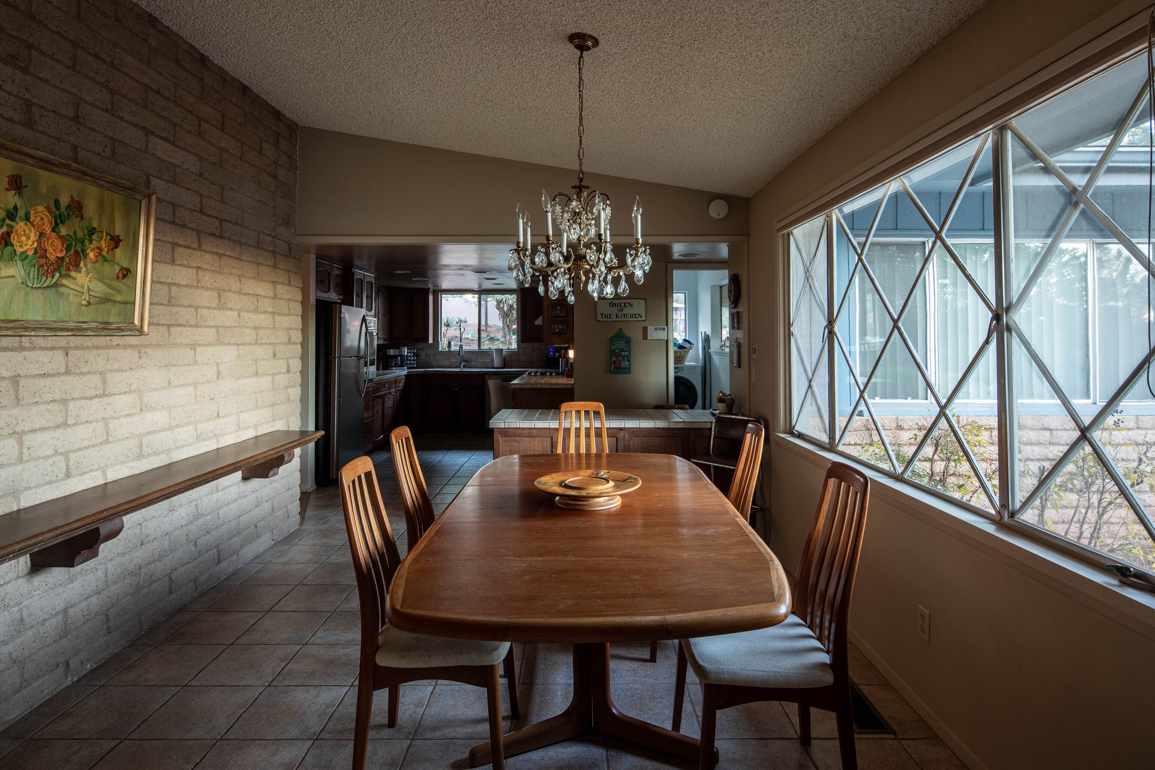 Un comedor con mesa y sillas de madera, una araña y vistas amplias a través de grandes ventanales.