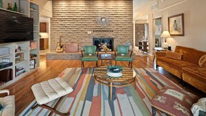 Un salon avec un mur en pierre, une cheminée, un téléviseur et un canapé.