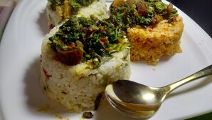 Une assiette contenant trois portions de riz, chacune garnie d’un mélange de légumes différent.