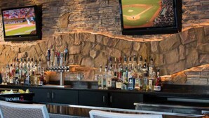 A bar area with a stone wall, multiple TVs, and a variety of liquor bottles. - Marriott Desert Springs II, Luxury 1 bedroom villa (Palm Desert)