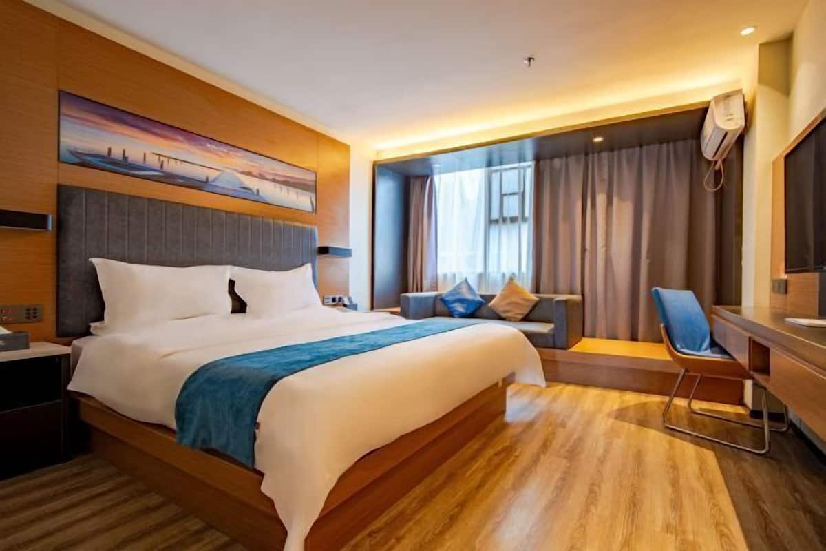 A modern hotel room with a large bed, a desk, and a seating area.