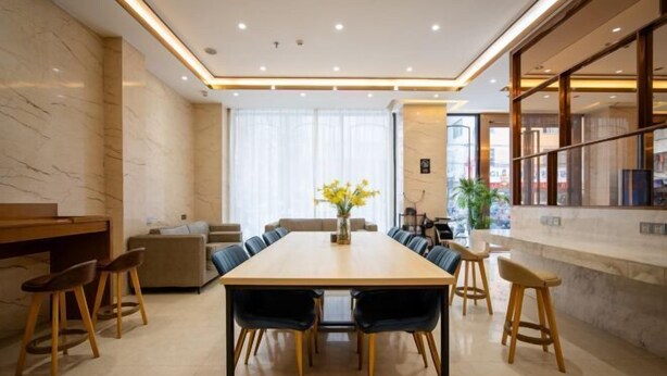 Un espace de restauration moderne avec une longue table, plusieurs chaises et un vase de fleurs.