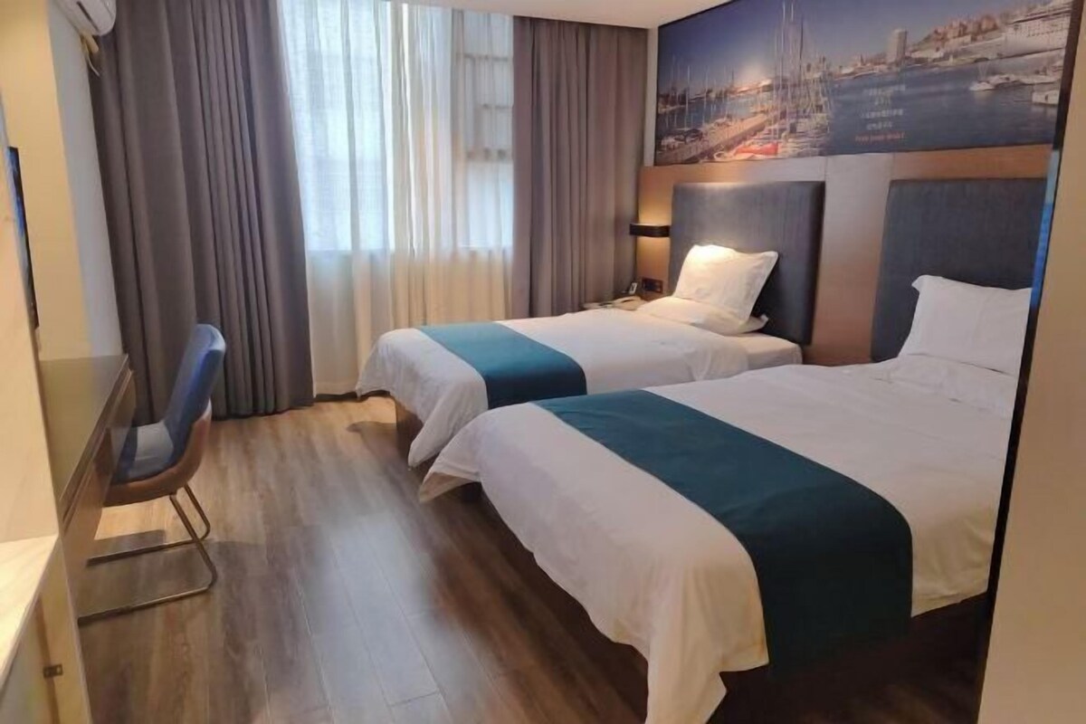 Habitación de hotel con dos camas, un escritorio y una silla.