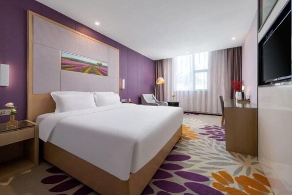 A hotel room with a large bed, a desk, a chair, a TV, and a painting on the wall. - Lavande Hotels (Zhuhai Tangjia University Town) (Zhuhai)