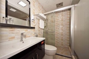 Un baño con lavamanos, espejo, inodoro y cabina de ducha de vidrio.