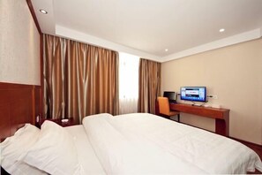 Ein Hotelzimmer mit Bett, Schreibtisch und Computer, sowie Vorhängen.