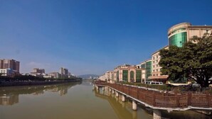A riverside view with a bridge, buildings, and a tree. - Meiguiyuan Business Hotel (Yongchun)