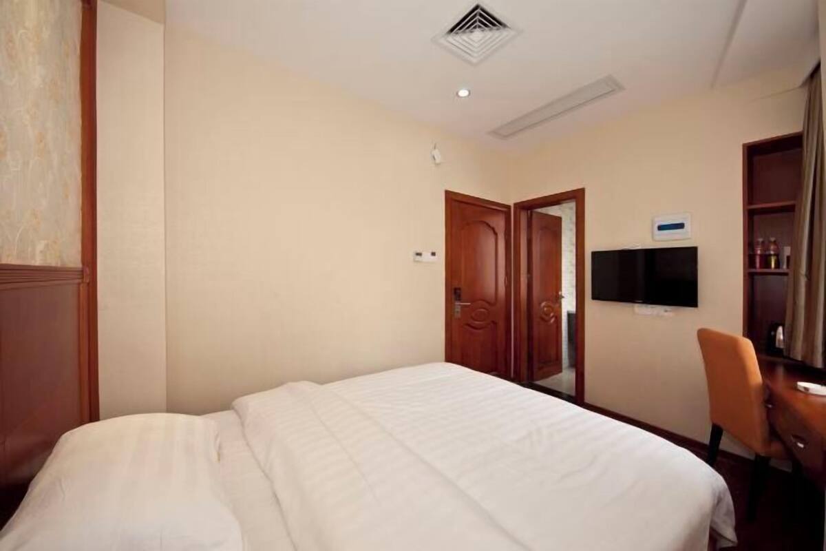 A hotel room with a bed, a television, a desk, and a wardrobe.