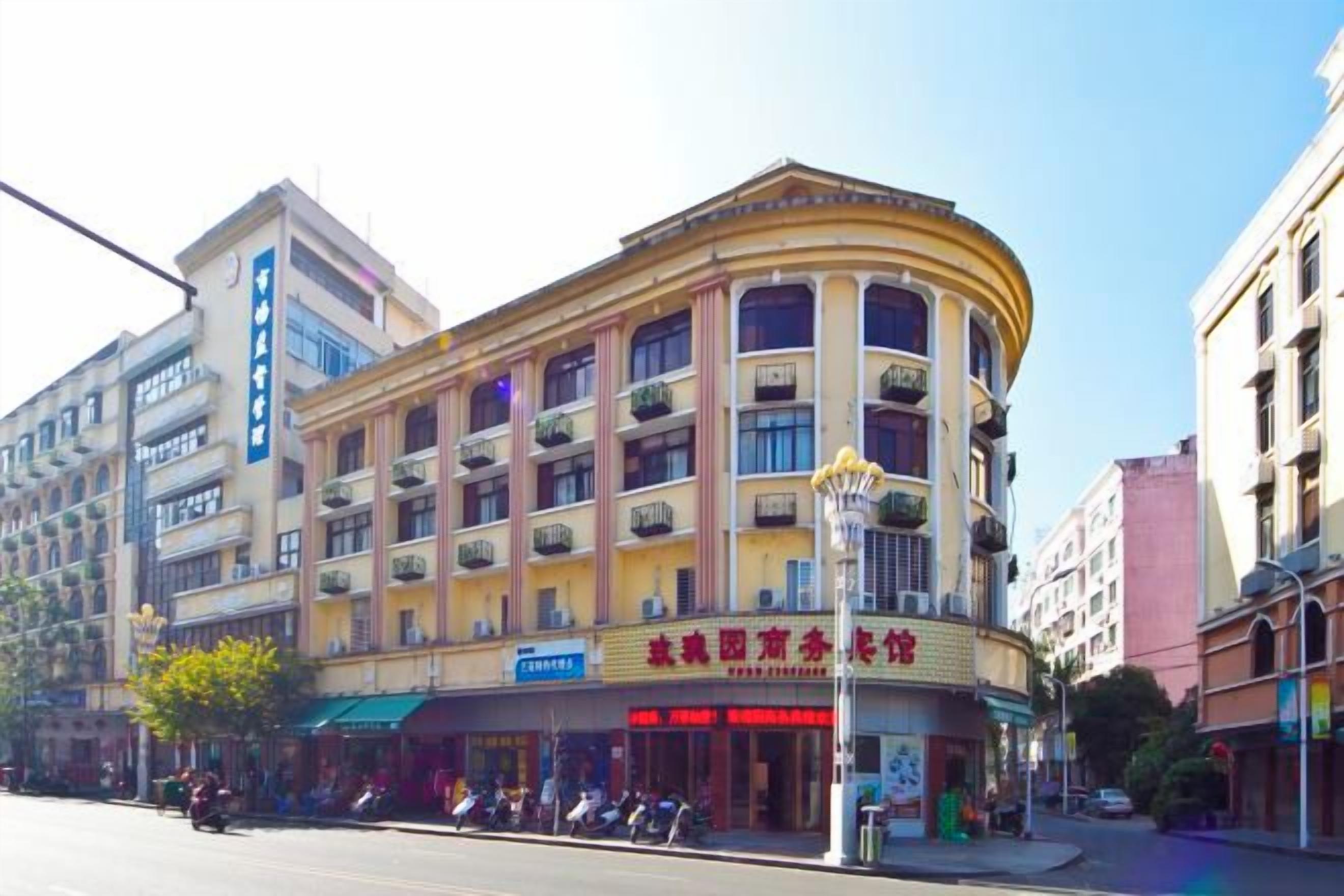 A multi-story building with a curved facade, balconies, and a ground-level entrance with signage.