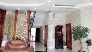 A spacious lobby with a staircase, a leather sofa, decorative panels, and a potted plant. - Meiguiyuan Business Hotel (Yongchun)
