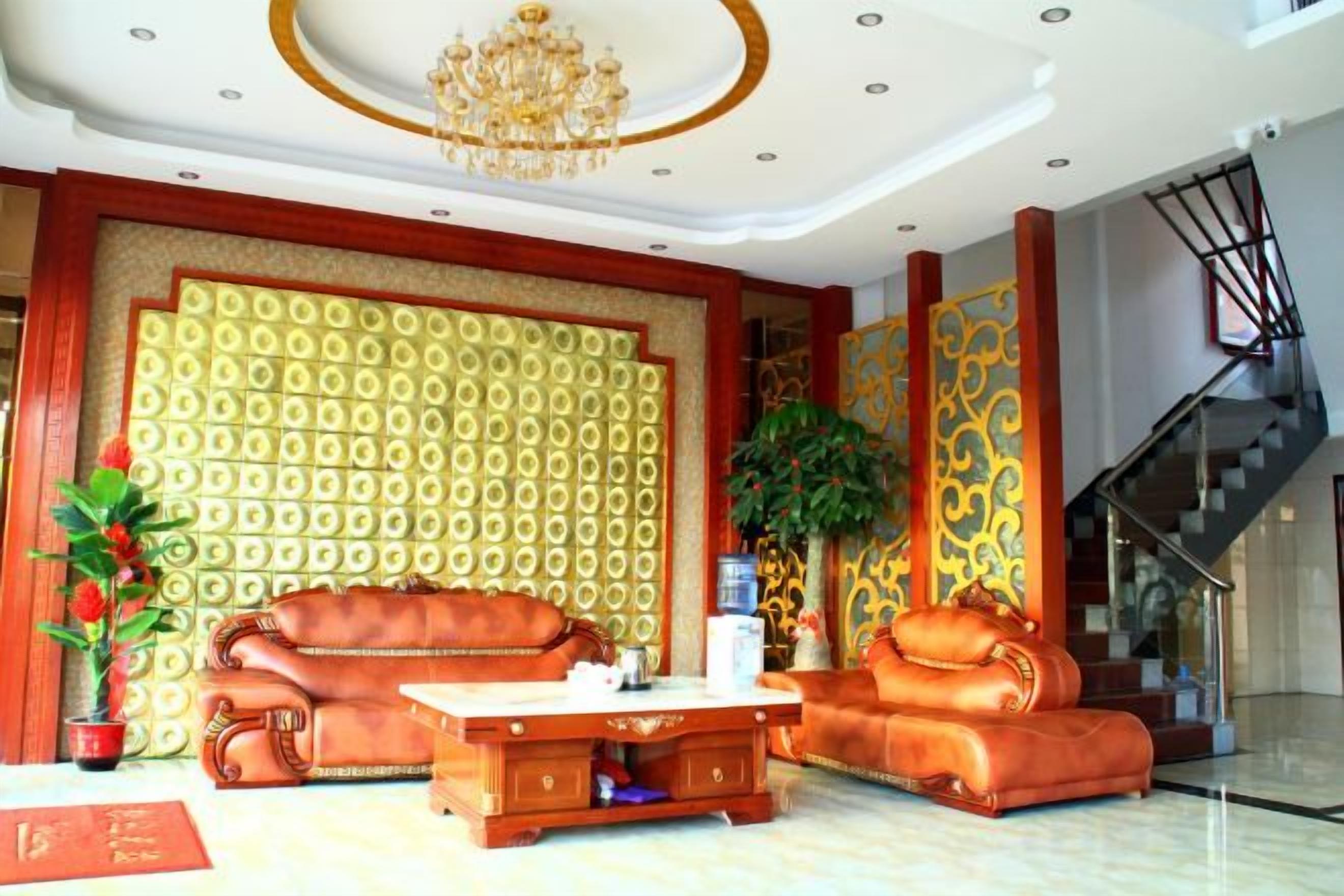 Eine geräumige Lobby mit hoher Decke, einem Kronleuchter, einer Treppe und einer Wand mit Muster.