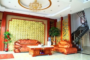 A spacious lobby with a high ceiling, a chandelier, a staircase, and a patterned wall. - Meiguiyuan Business Hotel (Yongchun)
