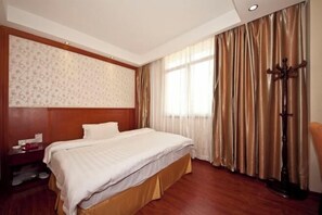 Ein Hotelzimmer mit einem großen Bett, einem Holzkopfteil, einem Nachttisch und einem Kleiderständer.