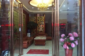 A hotel lobby with a sofa, a coffee table, and a potted plant. - Meiguiyuan Business Hotel (Yongchun)