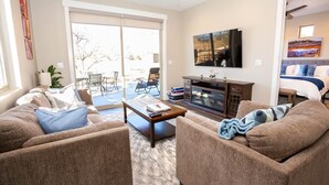A living room with a sofa set, a coffee table, a flat-screen TV, and a fireplace.