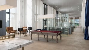 Uma sala de estar moderna com mesa de bilhar, assentos confortáveis e uma vitrine de vidro.
