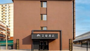 A modern hotel with a brown facade, a prominent entrance, and a sign with Chinese characters.
