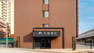 A modern hotel with a brown facade, a prominent entrance, and a sign with Chinese characters.